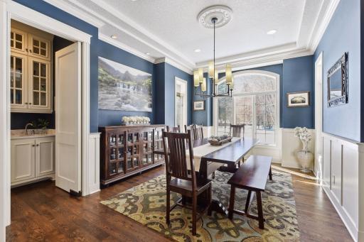 Formal dining room with beautiful wainscoting, box vault ceiling, and dual entry butler's pantry with sink and cabinets to the ceiling.