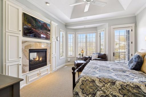 Breathtaking primary suite with tray vault ceilings, crown molding, double sided gas fireplace with marble surround, bayed window sitting area, atrium door to deck, & dual closets with organizers.