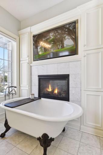 Tons of storage flanking this dual-sided gas fireplace and footed tub.