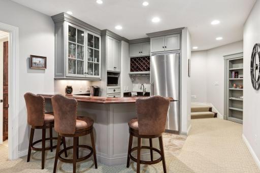 Entertainer's dream in this lower level with spectacular full bar area with seating and custom cabinets. Shhh...secret door at bookshelf at the bottom of the stairs!