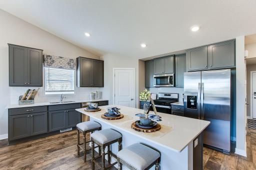 The Finnegan's open concept main level features a spacious kitchen with center island. Photos of model home. Colors and options may vary. Ask Sales Agent for details.