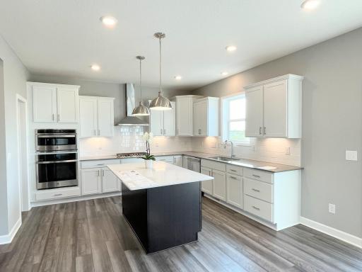 Who wouldn't love this bright, beautiful gourmet kitchen. Look at all of that lighting! LEDs, pendants, AND undercabinet lighting. Photos is of a different, sold home. Options, finishes and colors vary.