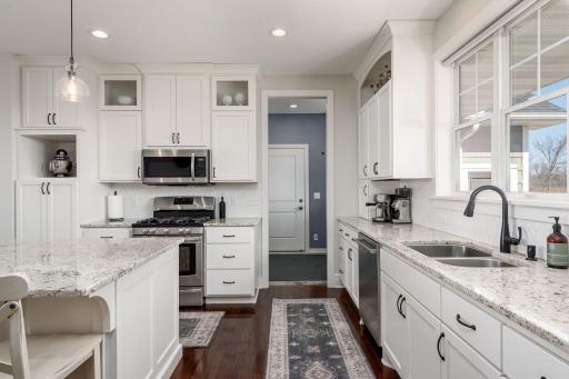 Gorgeous kitchen with solid wood floors, kitchen island and tons of cabinets. Area to the rear is the laundry and mud room and entry to the garage.