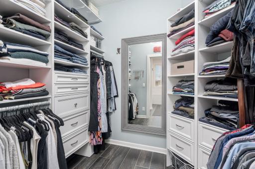 Large walk in primary closet with built in cabinetry and shelving.
