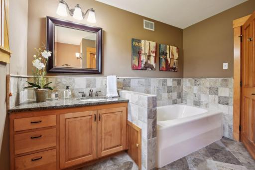 Main floor bedroom suite offers a luxurious jetted soaking tub and updated vanity