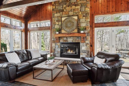 Gorgeous natural wood fireplace is surrounded by floor to ceiling stone