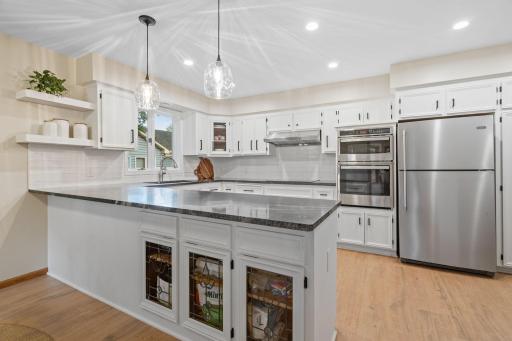 The kitchen shines with a new fridge, wall oven, microwave (2023), dishwasher, and cooktop (2022), complemented by freshly painted cabinetry and sleek granite countertops (2021)