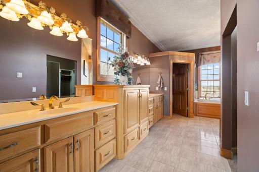 Indulge in the spa-like bathroom featuring dual sinks, heated tile floors, surround sound, a jetted tub, walk-in shower stall, and a walk-in closet with built-ins.