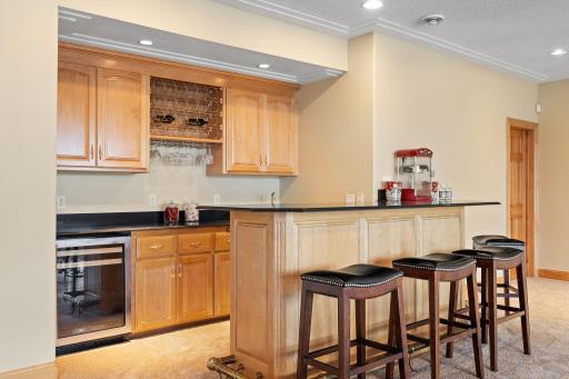 Built-in wet bar features a beverage fridge, sink, and peninsula with breakfast bar seating.
