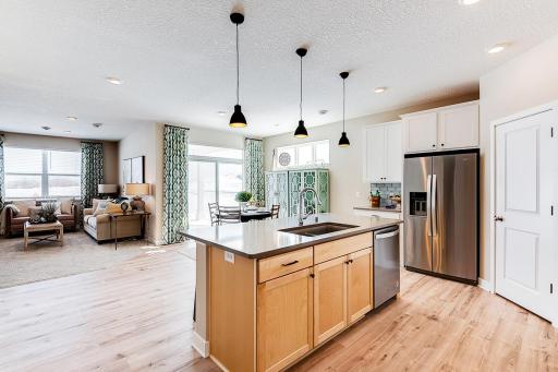 The home flow has the perfect balance of open concept with defined spaces for your kitchen, dining and living room needs. Model photo. Options and colors will vary in our available inventory homes.