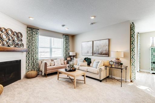 The homes tucked back living room with the corner gas fireplace makes for a cozy feeling home. Model photo. Options and colors will vary in our available inventory homes.