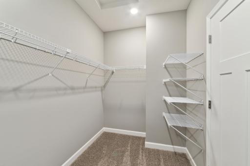 (Photo of model, actual homes finishes will vary) A large walk-in closet with mesh-wire shelving provides abundant room to store wardrobes, shoes, accessories and much more.