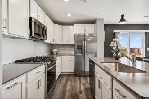 (Photo of decorated model, actual home's finishes vary) Enjoy plenty of seating at the kitchen island and dining area adjacent to the kitchen. Perfect for entertaining or having a family meal together.