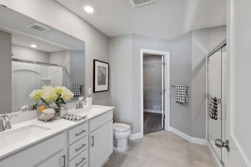 (Photo of decorated model, actual home's finishes will vary) Owner's bathroom with raised double-sink vanity, five-foot walk-in shower and a linen closet.