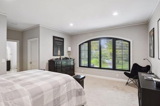 The bedroom itself features two walk-in closets and a large arched window, infusing the space with natural light.