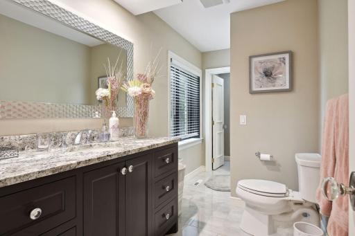 This room offers a walk-through to a bathroom with tile flooring, dark enameled vanity with granite top, and tile walk-in shower.