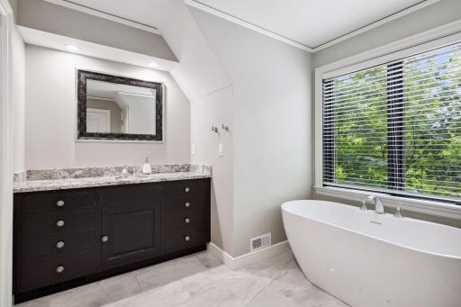 The bathroom boasts tile flooring, dark granite, an enameled vanity with granite countertops, walk-in shower, and luxurious soaking tub.