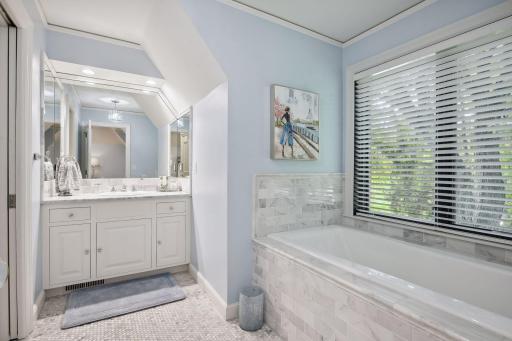 The adjacent bathroom features hexagon flooring, subway tile surrounding the soaking tub, granite countertops, white enameled vanity, and a tile shower.