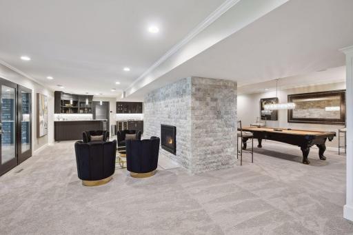 Descending to the lower level, accessed from the foyer, you'll find a space designed for entertainment and relaxation. A large gas fireplace, surrounded by stone, commands attention and creates a focal point for the room.