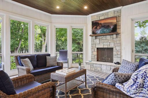 Continuing past the kitchen, you'll find access to the deck and screened porch. The screened porch has a stone fireplace with TV, speakers, and a ceiling fan to create an idyllic retreat.