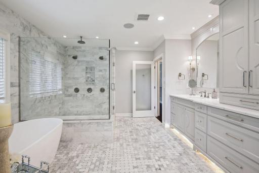 The primary bathroom is a haven of relaxation, featuring an oversized tile shower with double shower heads and rain shower, enameled double sink, oversized mirrors, decorative sconces, large soaking tub, and in-floor heating for ultimate comfort.