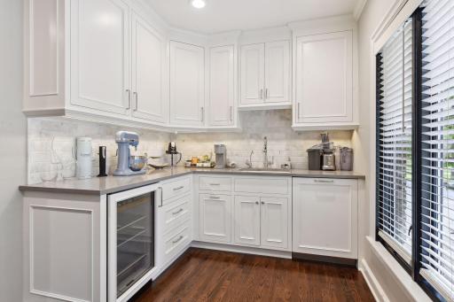 The scullery kitchen, adjacent to the main kitchen, boasts a walk-in pantry, sink, second dishwasher, and Sub-Zero mini-fridge, all seamlessly connected back to the formal dining room through two swing doors.