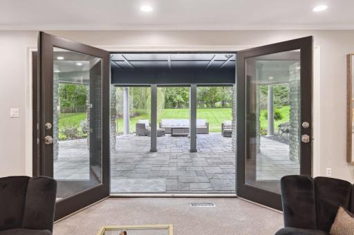 Double doors in the lower level lead to a walkout stone patio, partially covered by the deck above, and framed by decorative columns, providing an outdoor oasis for lounging and entertainment.