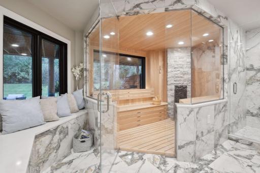 Opposite the bar is the sauna room, a luxurious retreat within the home. Built with tile from floor to bench, it features a large steam shower and large sauna, providing a spa-like experience.
