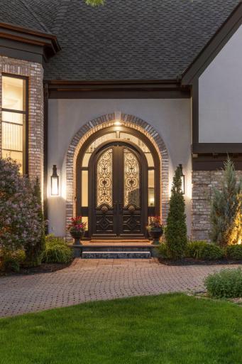 The stone walkway leads you to a massive arched doorway and windows, all finished in a sleek, elegant black.