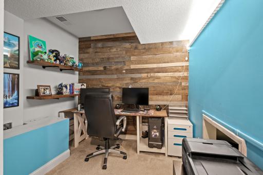 A lower level office space with a wood paneled wall providing rustic charm.
