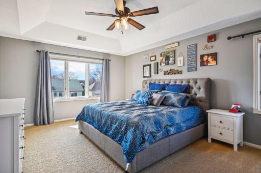 Owner's bedroom with raised ceiling architecture and fan.