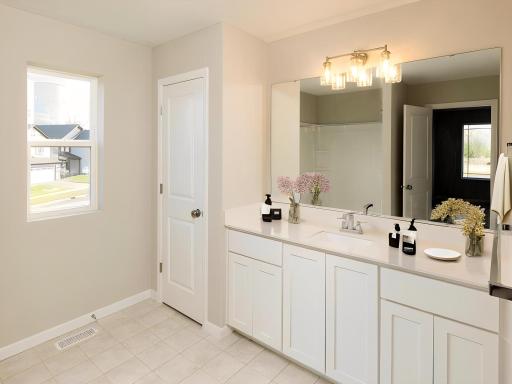 Photo taken of different home with similar plan & finishes virtually staged. Primary suite private bath features a spacious vanity and linen closet with window.