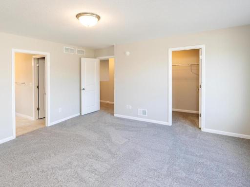 Photo taken of different home with similar plan & finishes virtually staged. Upper level primary suite features a spacious walk-in closet and private bath.