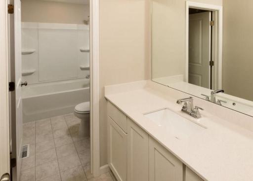 Photo taken of different home with similar plan & finishes virtually staged. Upper level main bath features a spacious vanity and separate room including a tub/shower and stool with door for added privacy.