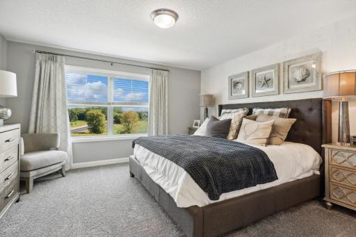 (Photo of a decorated model, actual homes finishes will vary) The spacious owner's suite is large enough for a king-sized bed and accessories.