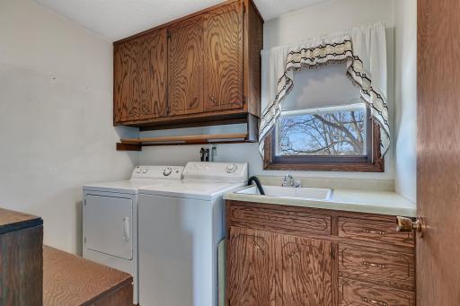 Main level laundry room with sink and storage cabinetry.
