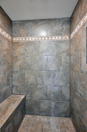 A close up view of the tile shower with a seat.