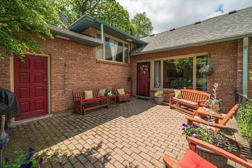This inviting paver patio deck gives you a glimpse of the comfort of home, with plenty of spaces to sit and relax. Touches like oversized windows down to the red carved door create a uniquely charming ambience to this home.