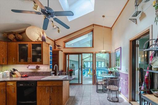 The vaulted kitchen has a skylight, granite countertop, solid oak cabinets, broom closet, tile flooring, and an eat-in dining space that overlooks the pool.