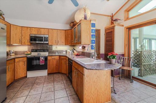 Another view of the kitchen, with its granite countertops and access to the pool room. A half bath lies between the peninsula counter and the pool area.