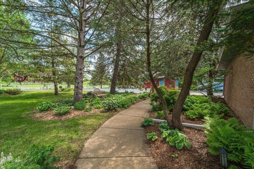 This curved sidewalk lined by perennials leads from the driveway to the back paver patio, or follow the walkway to the stables.