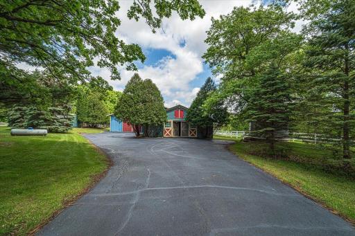 The blue and red stables are as picturesque as the home and setting, with French barn doors, mature trees and white picket fences.