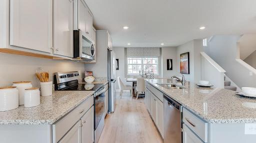 The spacious kitchen flows between the family room and eating area for convenience. Model picture shown. Colors and finishes may vary.