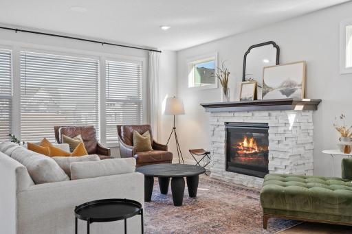 The informal living room has oversized windows and a gas fireplace with stacked stone.