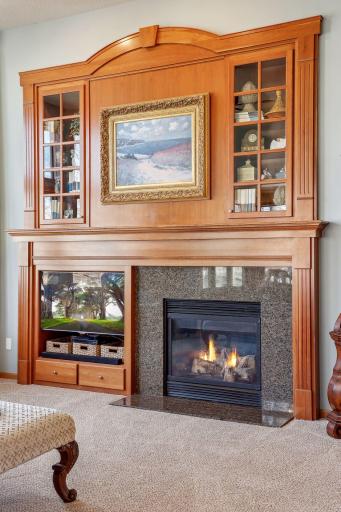 Gas fireplace with granite surround, media center and display shelves in the living room