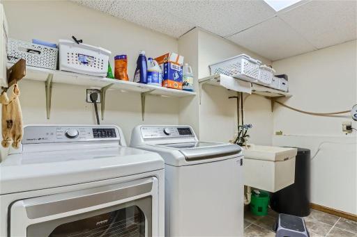 The laundry room is quite spacious with shelving. There is an owned water softener as well here.