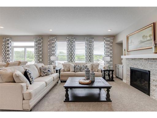 The family room is enhanced by a gas fireplace - which serves as a cozy gathering area, and highlights a space that's flooded in natural light via these three soaring windows! Photo of model home, color and options will vary.