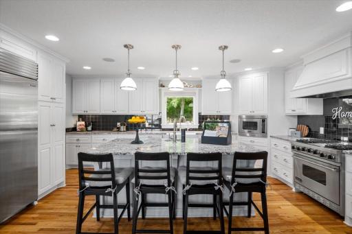 Welcome to the chef's kitchen. Large center island with breakfast bar seating, Sub Zero fridge and freezer, Viking convection microwave, oven, range and stove, farmhouse kitchen sink, and two hidden trash drawers. Granite countertops.