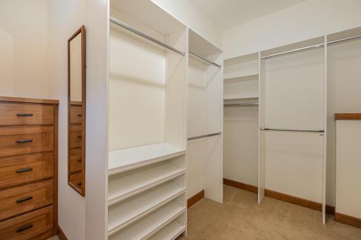 The primary bedroom suite also features this walk-in closet with: a 9 foot knock down ceiling, closet organizer, and custom, built-in dresser. The wall mirror is included.