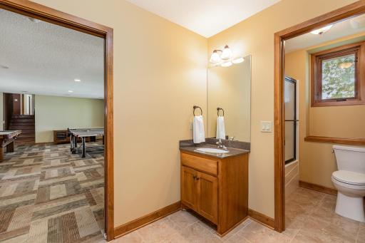 The full bathroom in the lower level features a tub with glass shower doors, and ceramic tile floor. It also offers a separate sink/vanity area in the lower level mudroom.